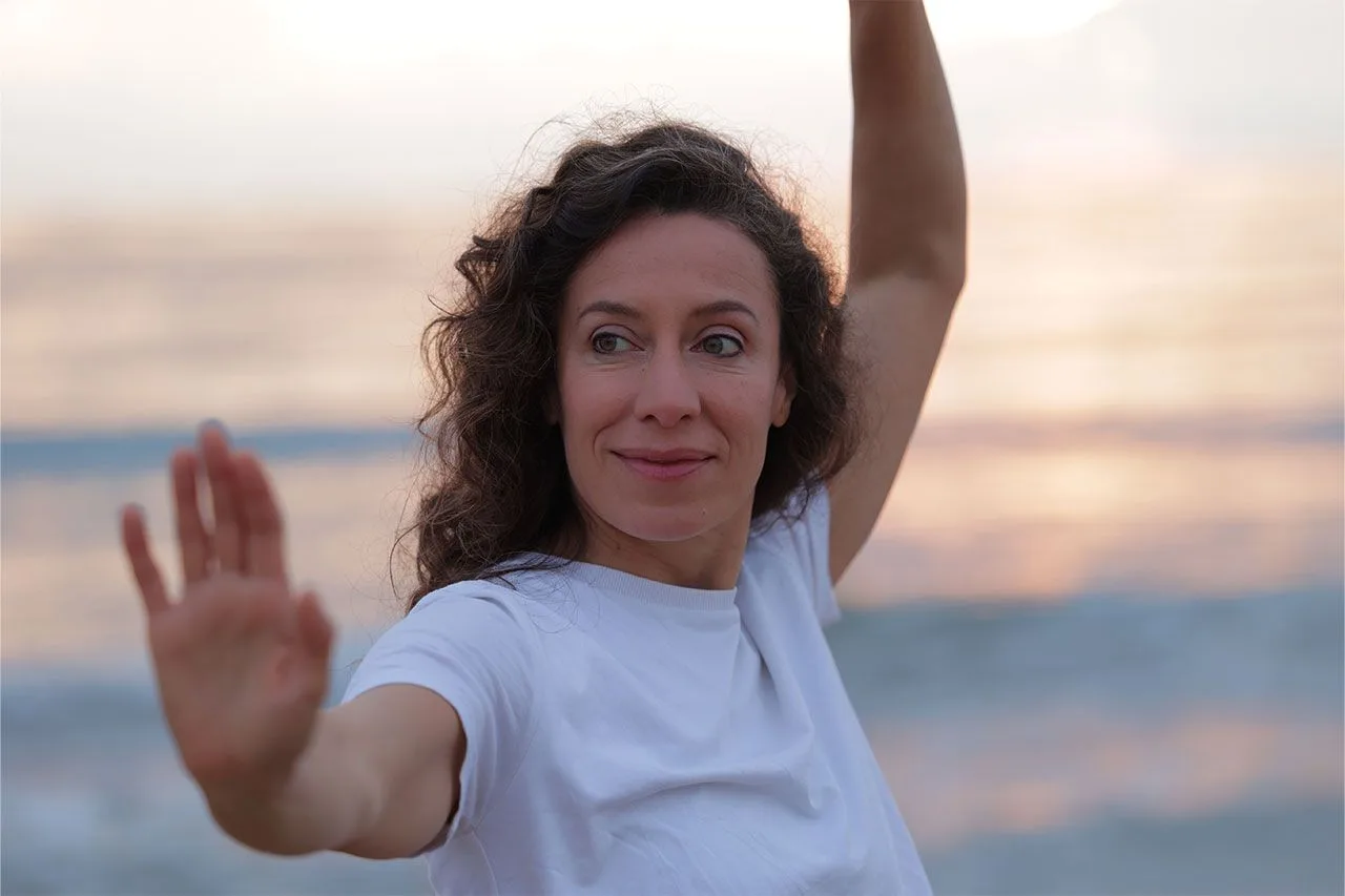 Sara Tau guiando un movimiento consciente frente al mar al atardecer