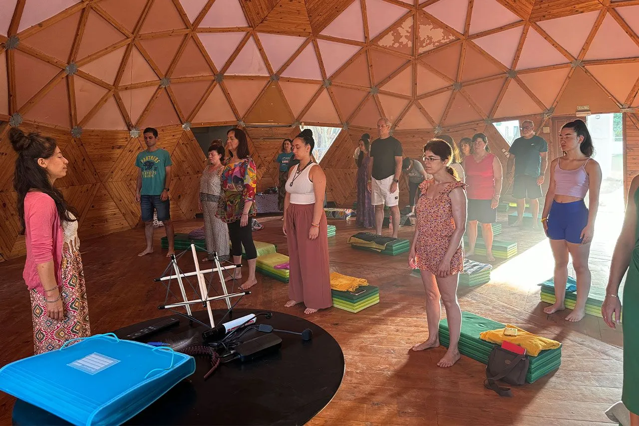 Grupo de alumnos en una clase de movimiento consciente dentro de una cúpula de madera